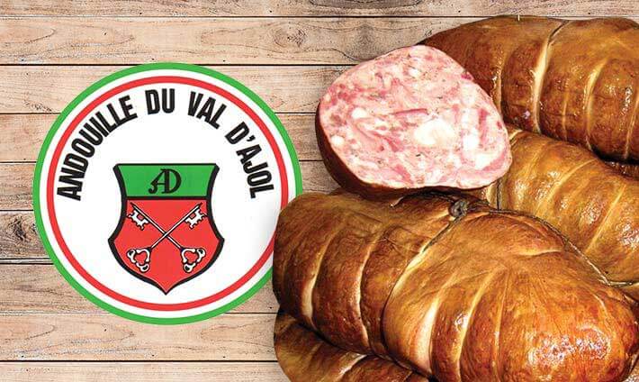 Plusieurs andouilles sur fond de bois avec le logo de l’andouille du Val d’Ajol