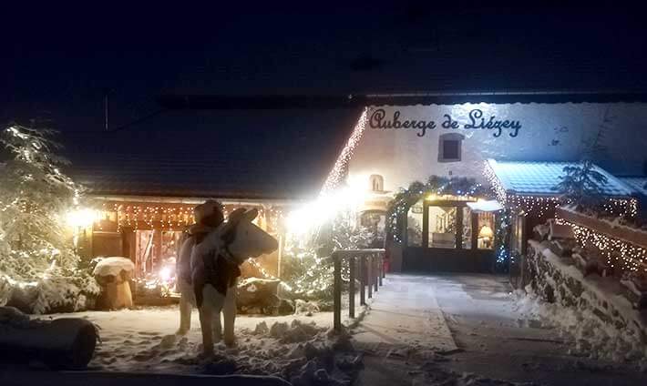 Devant l’Auberge sous la neige en soirée