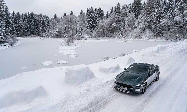 Voiture Mustang dans u décor sauvage enneigé près d’un lac