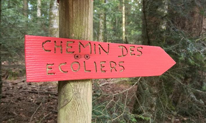 Pancarte rouge indiquant la direction pour le chemin des écoliers