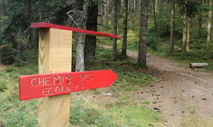 Pancarte rouge de direction pour le chemin des écoliers