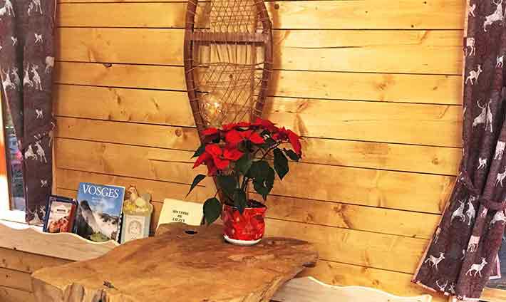 Petite table en bois massif avec un pot de fleur rouge et une ancienne raquette au mur, décor tout bois