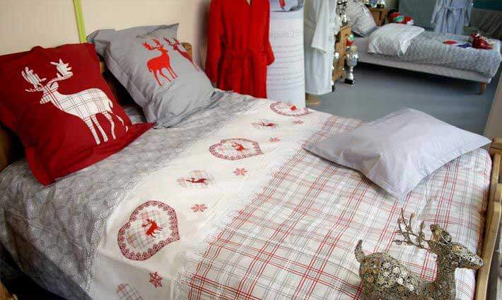 Lit avec une parure rouge et grise aux motifs traditionnels vichy