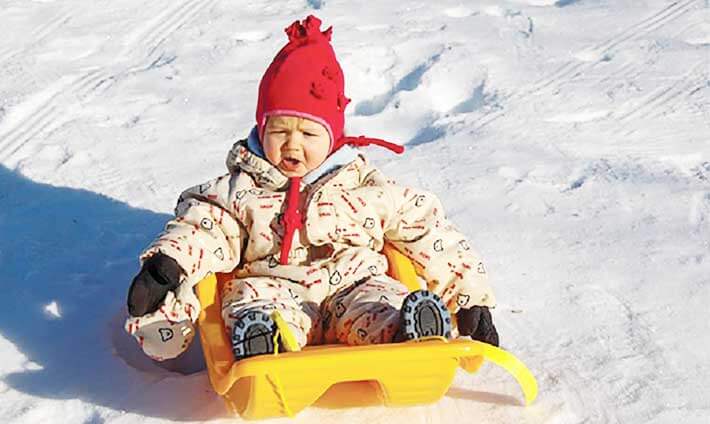 Un enfant dans une luge jaune qui descend une pente