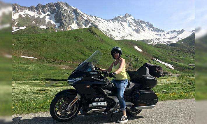 Sandrine sur sa moto avec les Alpes en fond
