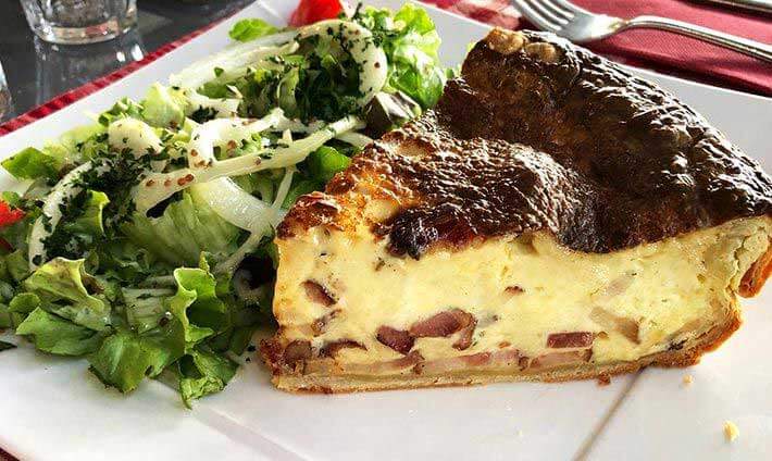 Assiette avec belle part de quiche épaisse, salade, (...)