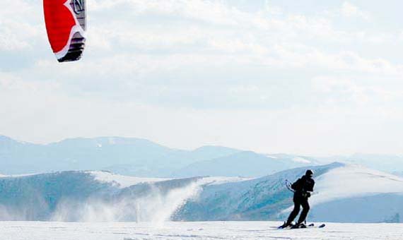 Eu dessus des sommets enneigés, une personne en snowkite