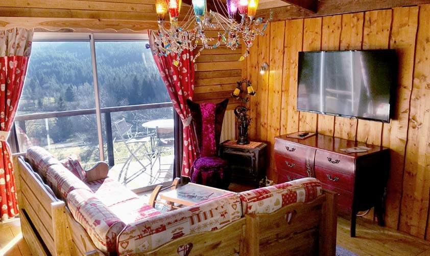 Grande chambre avec un lit double et un canapé, grande baie vitrée et décoration tout en bois